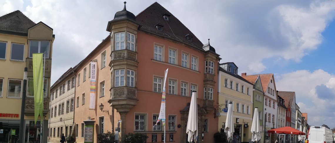 Ein dreigeschossiges Eckhaus mit einem markanten Erker an der Geb&auml;udeecke. 