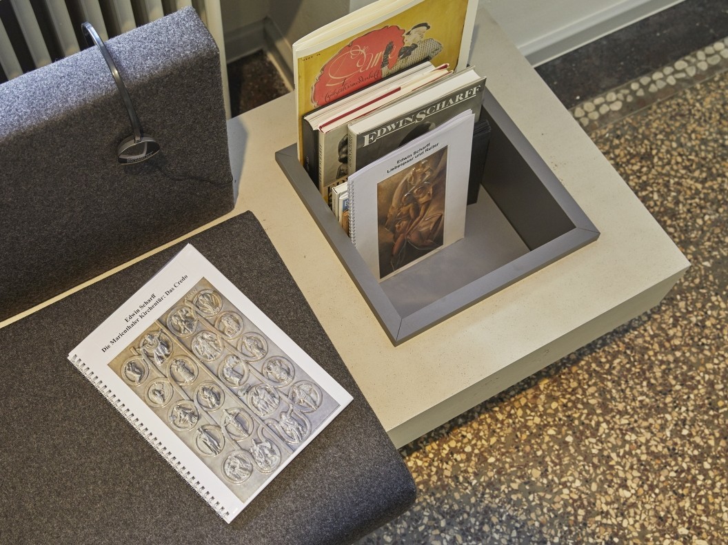 B&uuml;cher und Brosch&uuml;ren sind griffbereit neben einer Sitzgelegenheit.