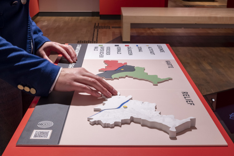 Eine Hand betastet einen Tastplan.