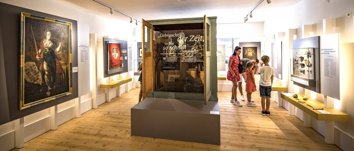 Zwei Erwachsene und zwei Kinder nutzen eine H&ouml;rstation in einem modernen Museumsraum.