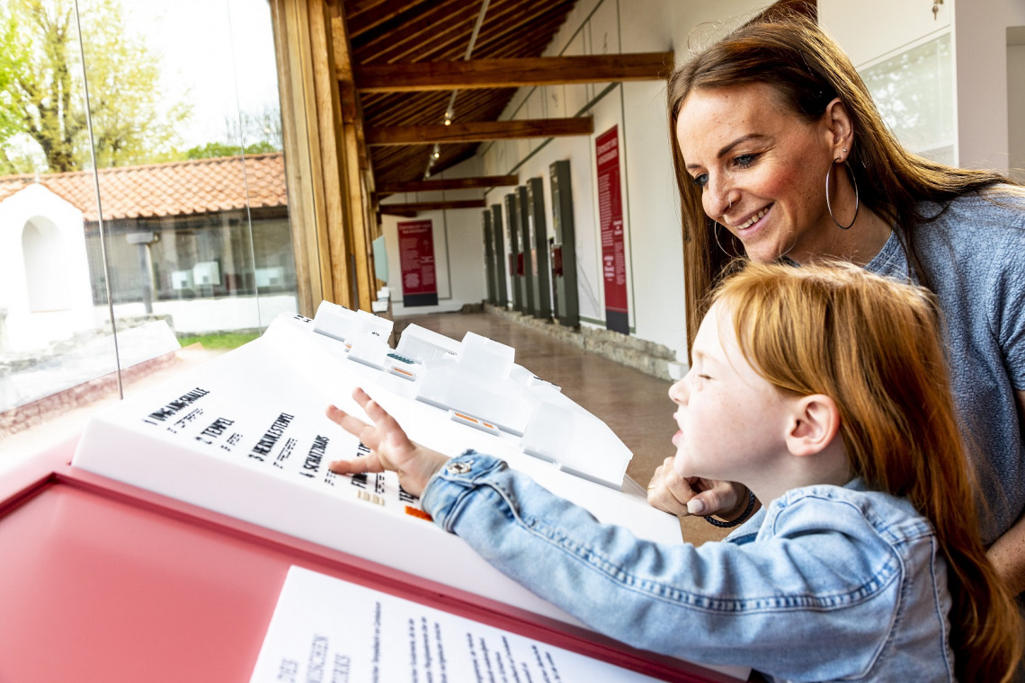 Ein M&auml;dchen mit geschlossenen Augen tastet die Schrift auf einer Tafel ab. 
